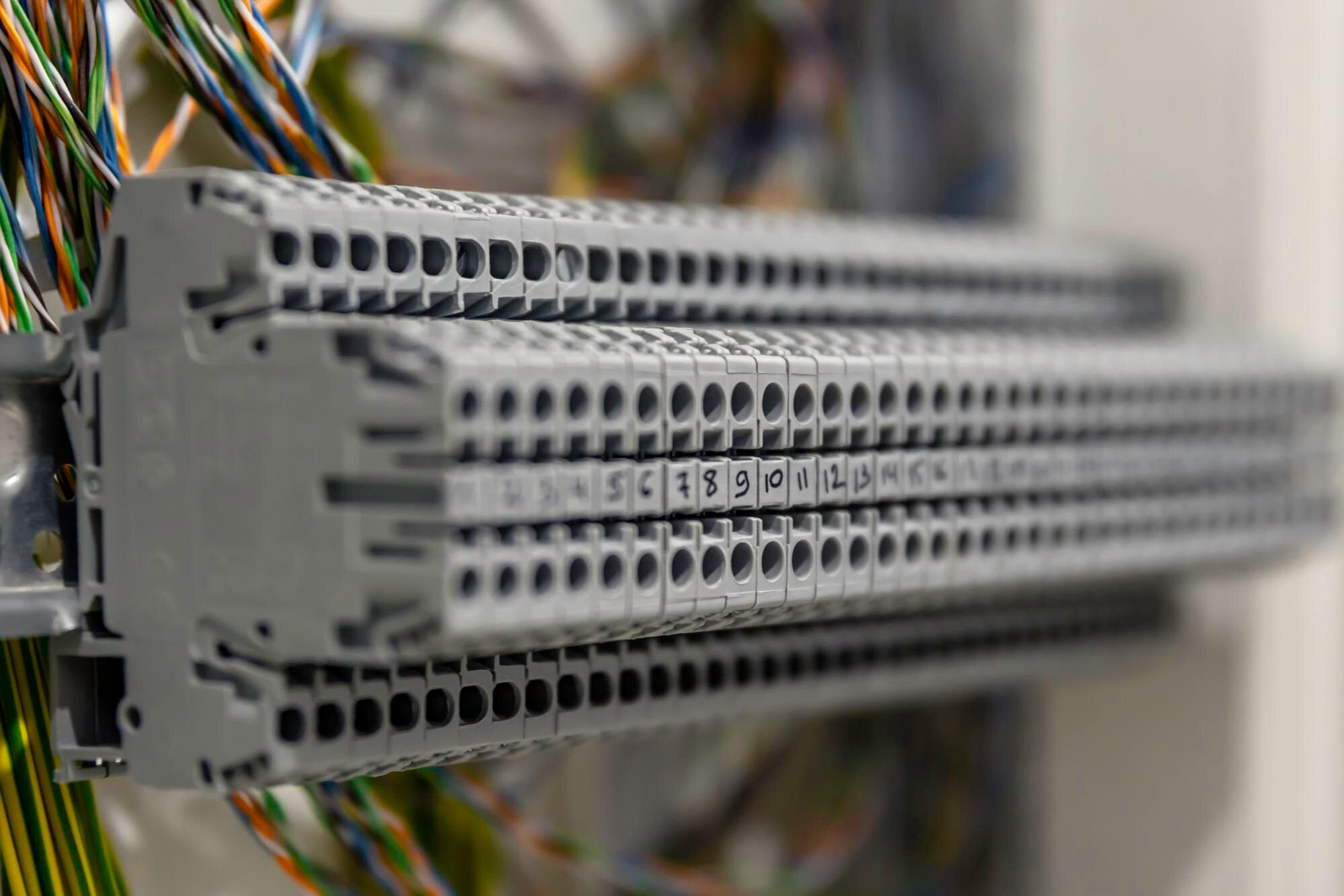 Close-up of a structured wiring panel with rows of numbered ports and multi-colored wires in a server room. This image highlights the technical infrastructure behind enterprise connectivity and high-speed internet for business.