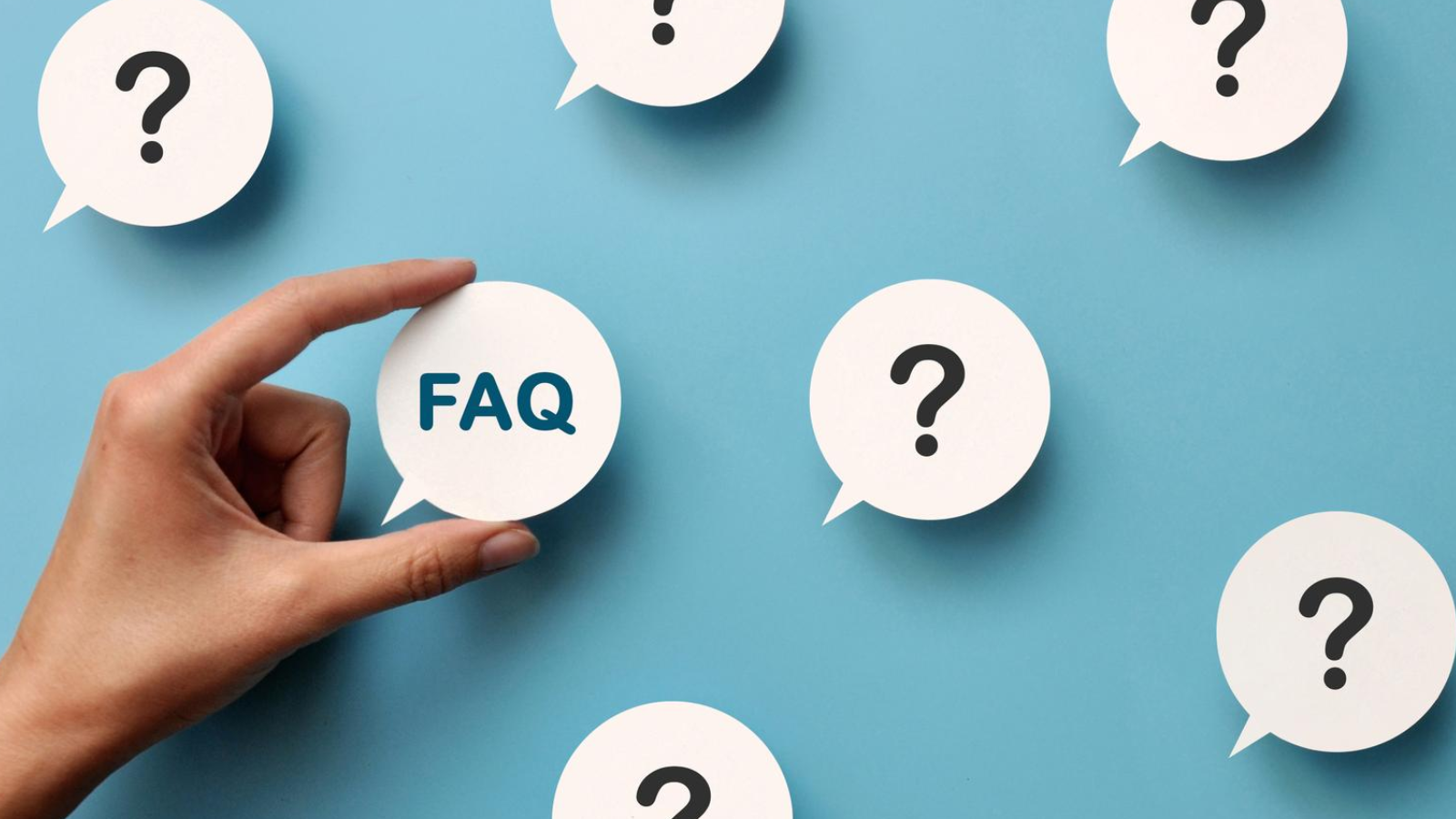 Hand holding a speech bubble labeled FAQ among question marks on a blue background.