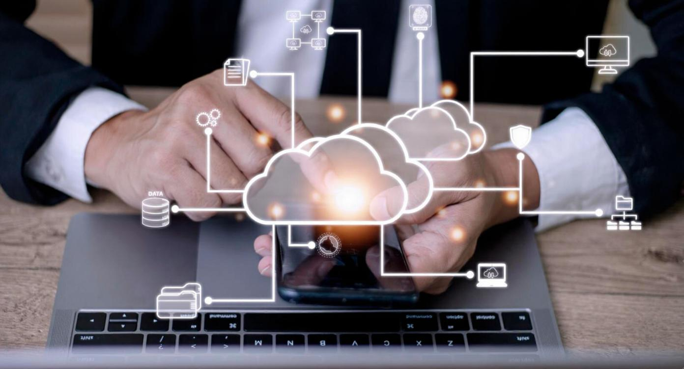 Hands using a smartphone and laptop with cloud and data icons, highlighting enterprise connectivity across public and private clouds using application programming interfaces (API).