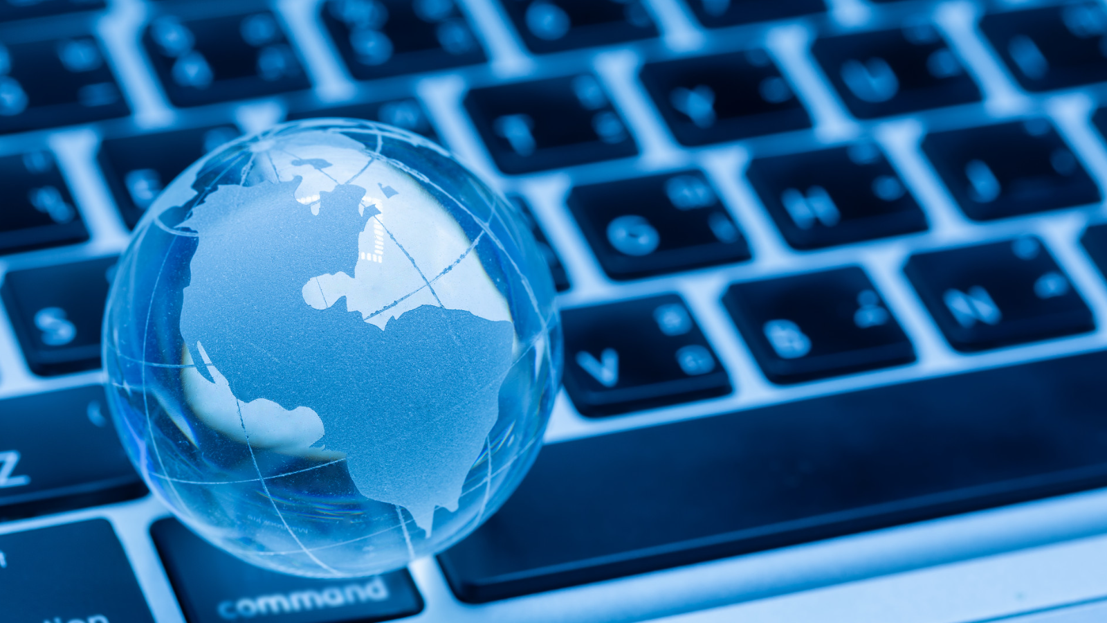 Glass globe resting on a computer keyboard symbolizing the choice between local network management and outsourced network support.