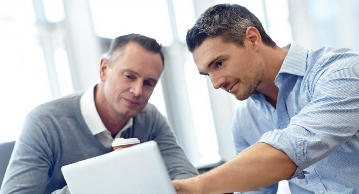 Two business users collaborating over a laptop, showing how PS Lightwave supports enterprise applications, customer information protection, data encryption, and other benefits.