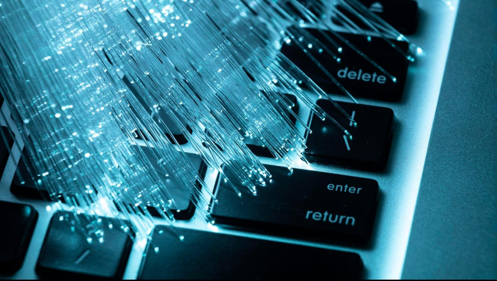 Close-up of glowing fiber optic cables on a computer keyboard, illustrating Fiber Optic Internet Houston and high-speed data transmission technology.